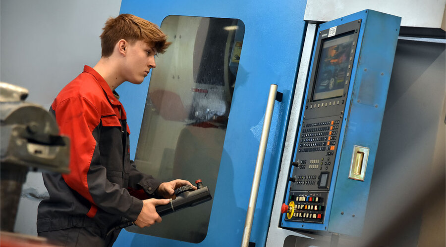 Das Bild zeigt einen Lehrling in der Werkzeugbautechnik, der konzentriert eine Erodiermaschine bedient. Seine Hände sind geschickt damit beschäftigt, die Maschine zu steuern, während er den Bearbeitungsprozess überwacht. Die Szene vermittelt den Eindruck von Lernbereitschaft und praktischer Erfahrung im Umgang mit hochpräzisen Werkzeugmaschinen.