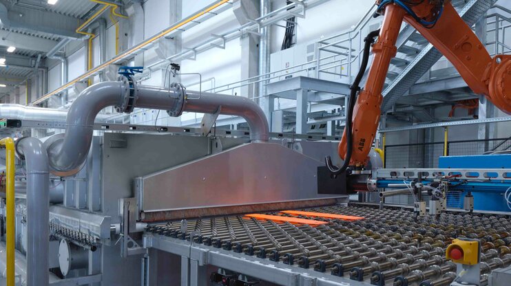Automatizovaná linka pro tváření za tepla s robotickou manipulací a rozžhaveným ocelovým plechem pro výrobu vysokopevnostních lehkých dílů.
