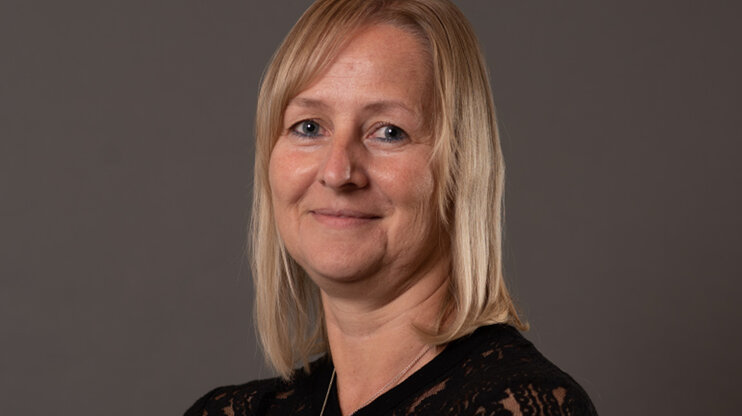 Portrét Klaudie Weingartsbergerové, zaměstnankyně interního obchodního oddělení ve společnosti weba, před neutrálním šedým pozadím.