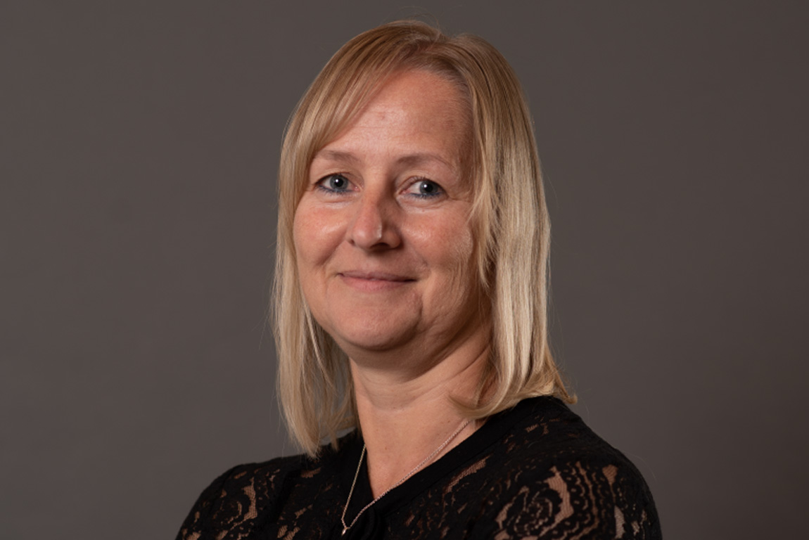 Portrét Klaudie Weingartsbergerové, zaměstnankyně interního obchodního oddělení ve společnosti weba, před neutrálním šedým pozadím.